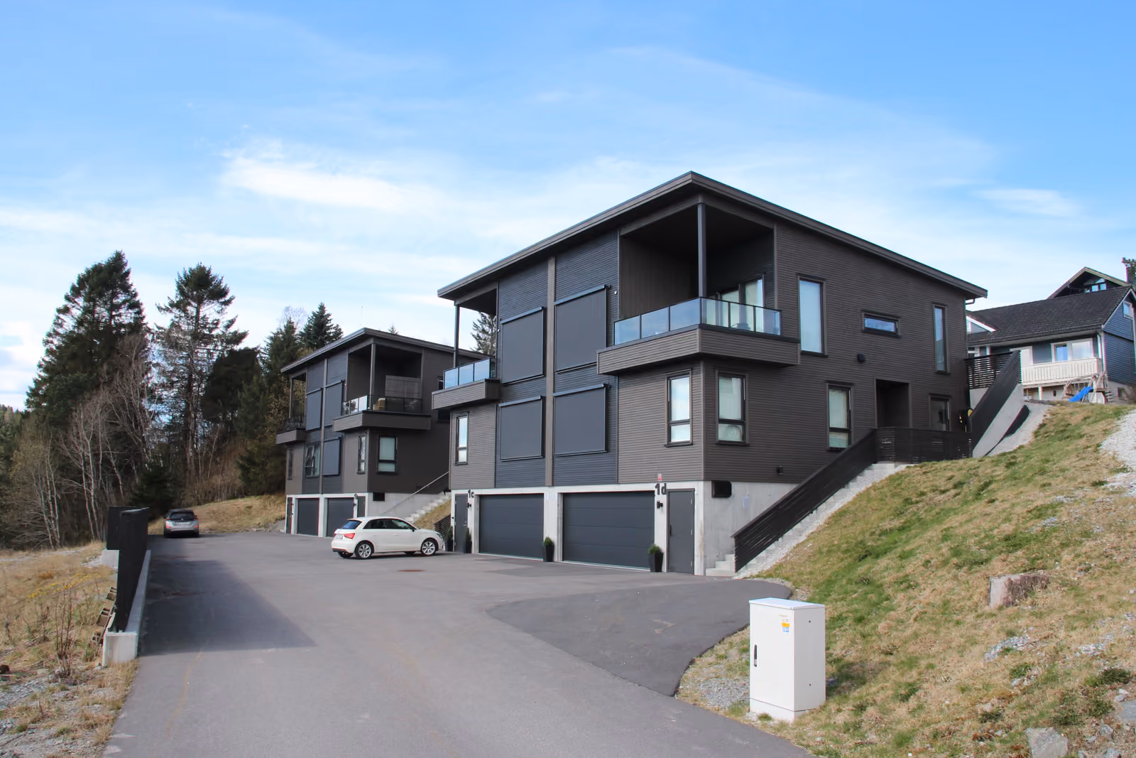 Tomannsboligene i Lerstadlia i Ålesund sett fra veien, med garasjer i underetasjen og balkonger