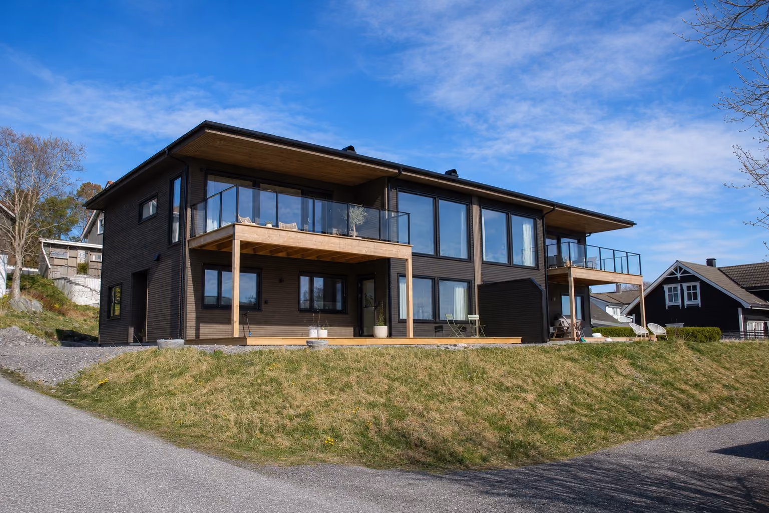Modern duplex at Skjongstranda on Valderøya with dark cladding, timber detailing and glass railings